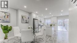 Open-concept kitchen and dining area featuring recessed lighting, extensive white cabinetry, and stainless steel appliances - 