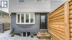 Gray brick facade with a bay window and a dark entry door featuring decorative glass - 