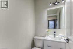 White vanity with integrated sink, black single-handle faucet, wall-mounted mirror, and track lighting fixture - 