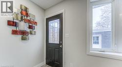 Entryway with a black door featuring decorative glass inserts, a white window frame, and light gray wall paint - 
