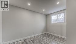 Recessed ceiling lighting, wood-finish flooring, white trim, and a window with white framing - 