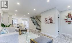 Recessed lighting illuminates the open-concept living space with light-toned walls and wood-finish flooring - 