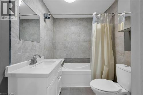 Bathroom featuring a white vanity with integrated sink, chrome faucet, wall-mounted mirror, and tiled shower surround with a built-in tub - 9 Melrose Avenue S Unit# Upper, Hamilton, ON 