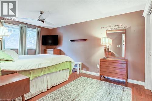 Wood-finish flooring, multiple windows providing ample natural light, ceiling fan, and built-in closet with sliding doors - 106 Appleford Road, Hamilton, ON 
