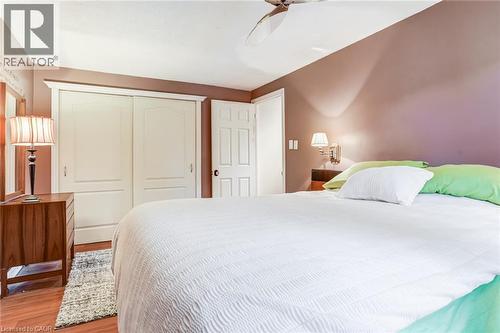 Wood-finish flooring with a ceiling fan, built-in closet with sliding doors, and a wall-mounted light fixture - 106 Appleford Road, Hamilton, ON 
