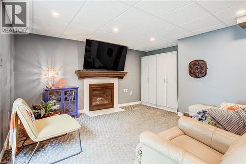 Recessed lighting illuminating a carpeted floor, built-in fireplace with a wood-finish mantel, and integrated storage cabinetry - 106 Appleford Road, Hamilton, ON 