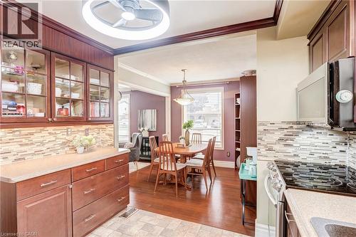 Kitchen featuring wood-finish cabinetry with glass-front uppers, mosaic tile backsplash, and built-in microwave - 106 Appleford Road, Hamilton, ON 