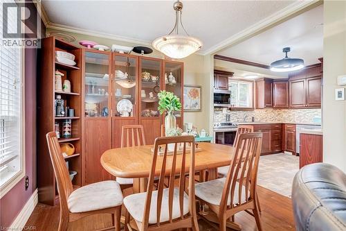 Built-in cabinetry with glass-front display, overhead lighting, wood-finish flooring, and crown molding - 106 Appleford Road, Hamilton, ON 