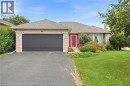 Brick exterior with a dark garage door, red entry door, and a low-slung roofline - 9 Country Club Road, Cayuga, ON 