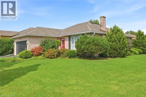 Brick exterior with a peaked roof, attached garage, and a prominent brick chimney - 9 Country Club Road, Cayuga, ON 