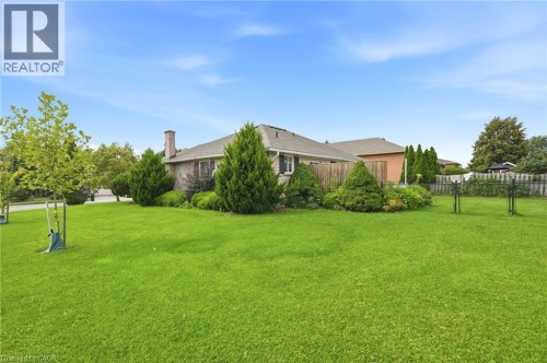 Expansive lawn area with mature landscaping, a privacy fence, and a brick exterior dwelling - 9 Country Club Road, Cayuga, ON 