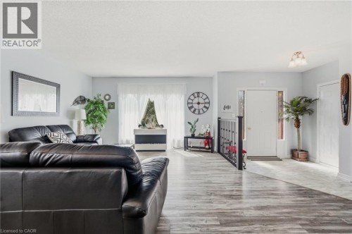 Spacious interior with wood-finish flooring, light grey wall paint, and ample natural light from a large window - 9 Country Club Road, Cayuga, ON 