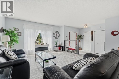 Light wood-finish flooring, broad window with sheer coverings, and a metal stair railing - 9 Country Club Road, Cayuga, ON 