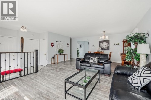 Wood-finish flooring throughout, with a decorative iron railing and white interior doors - 9 Country Club Road, Cayuga, ON 