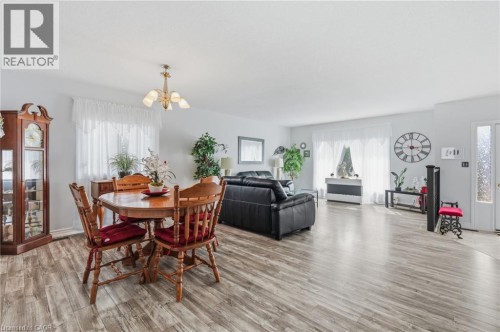 Open-concept living area featuring wood-finish flooring, white walls, and multiple windows - 9 Country Club Road, Cayuga, ON 