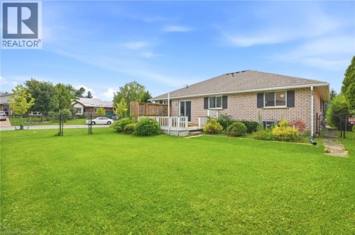 Expansive green lawn, brick exterior, multi-pane windows, and a raised wood-finish deck - 9 Country Club Road, Cayuga, ON 