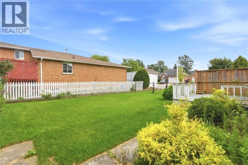 Expansive green lawn, white picket fence, wood deck, brick exterior, and mature landscaping - 9 Country Club Road, Cayuga, ON 