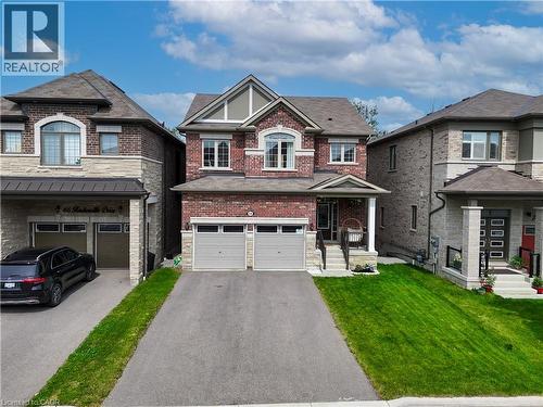 Brick and stone facade, covered front porch, two-car garage, paved driveway, and manicured lawn - 68 Barkerville Drive, Whitby, ON 