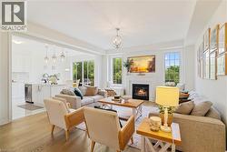 Open-concept living area with wood-finish flooring, a fireplace with mantel, and multiple windows - 