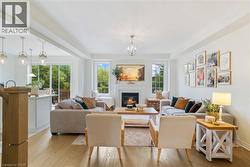 Open-concept living space featuring wood-finish flooring, a fireplace with a mantel, and recessed lighting - 