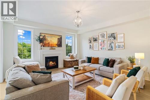 Living area featuring a fireplace with a white mantel, wood-finish flooring, and multiple windows - 68 Barkerville Drive, Whitby, ON 