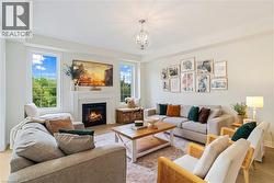 Living area featuring a fireplace with a white mantel, wood-finish flooring, and multiple windows - 