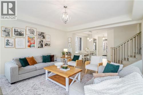 Recessed lighting throughout, contemporary chandelier, wood-finish flooring, staircase with painted balusters, and crown molding - 68 Barkerville Drive, Whitby, ON 