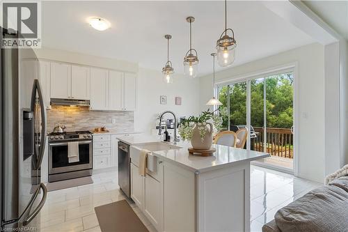 Modern kitchen featuring white cabinetry, stainless steel appliances, a center island with a farmhouse sink, and polished tile flooring - 68 Barkerville Drive, Whitby, ON 