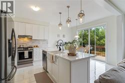 Modern kitchen featuring white cabinetry, stainless steel appliances, a center island with a farmhouse sink, and polished tile flooring - 