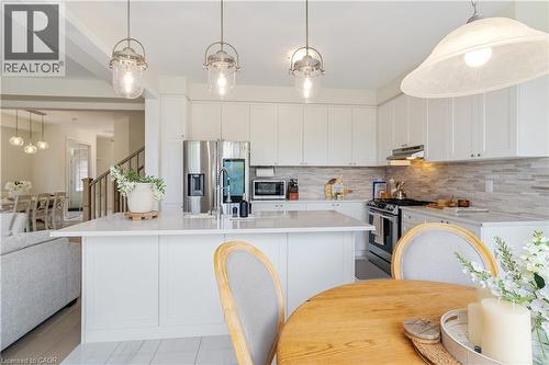 White cabinetry, stainless steel appliances, pendant lighting, light-toned countertops, and a tile backsplash - 68 Barkerville Drive, Whitby, ON 