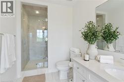Glass-enclosed shower with tile surround, white vanity with integrated sink, polished chrome fixtures, and a large wall-mounted mirror - 