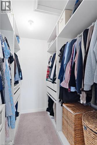Walk-in closet featuring built-in white shelving, integrated drawers, and ample hanging space - 68 Barkerville Drive, Whitby, ON 