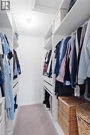 Walk-in closet featuring built-in white shelving, integrated drawers, and ample hanging space - 