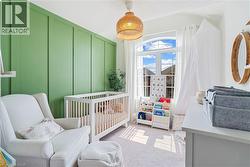 Board and batten accent wall, arched window with white trim, white window sheers, woven pendant light, and light-toned carpeting - 