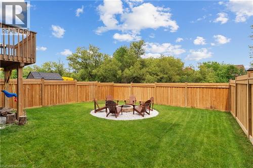 Fenced backyard with a manicured lawn, a gravel fire pit area, and a wood deck structure - 68 Barkerville Drive, Whitby, ON 
