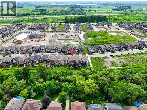 Aerial overview of a residential development featuring numerous single-family homes, surrounding green spaces, and a nearby undeveloped lot - 68 Barkerville Drive, Whitby, ON 