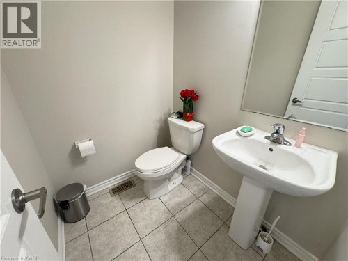 Pedestal sink, ceramic tile flooring, wall-mounted mirror, and a contemporary toilet - 67 Pointer Street, Cambridge, ON 