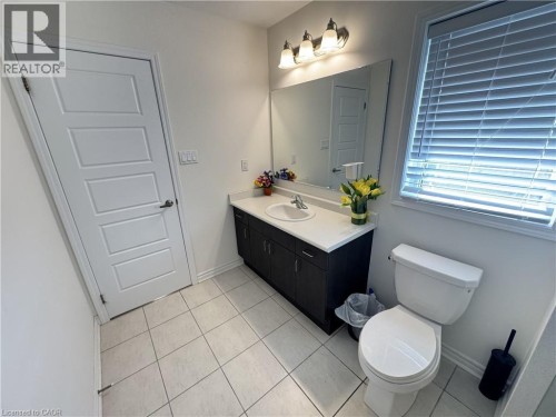 Vanity with a white countertop and undermount sink, large wall-mounted mirror, three-light vanity fixture, and tiled flooring - 67 Pointer Street, Cambridge, ON 