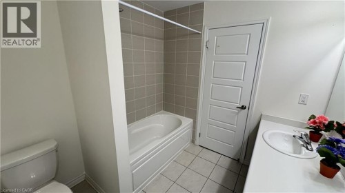 Bathroom with a built-in bathtub featuring subway tile surround, a built-in toilet, and a vanity with an integrated sink - 67 Pointer Street, Cambridge, ON 