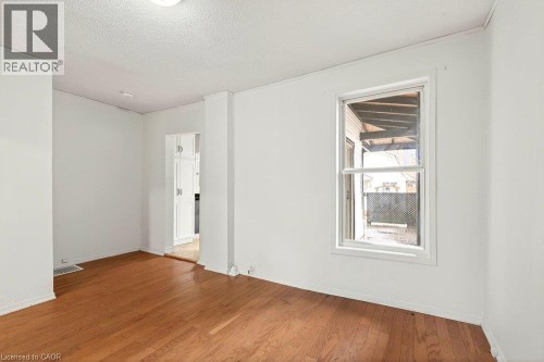 Hardwood flooring, painted walls, single-pane window, flush mount ceiling fixture, and baseboard trim - 23 Frederick Avenue, Hamilton, ON 