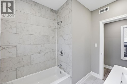 Bathtub with polished chrome fixtures, subway tile surround, and light gray wall paint - 98 Duke Street Unit# 2Nd, Hamilton, ON 