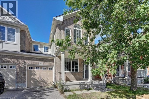 Brick veneer exterior with a covered porch, white columns, arched window, and an attached garage with a panel door - 103 Blackbird Circle, Cambridge, ON 