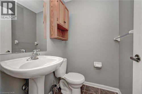 Pedestal sink with chrome faucet, large wall-mounted mirror, light wood-finish wall cabinet, and neutral wall paint - 103 Blackbird Circle, Cambridge, ON 