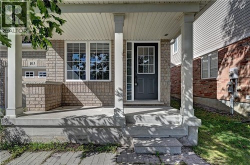 Brick and siding exterior featuring a covered porch, white-framed windows, and a panel-style entry door with divided lites - 103 Blackbird Circle, Cambridge, ON 