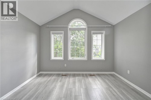 Vaulted ceiling, arched window, two vertical windows, light gray walls, and wood-finish flooring - 103 Blackbird Circle, Cambridge, ON 