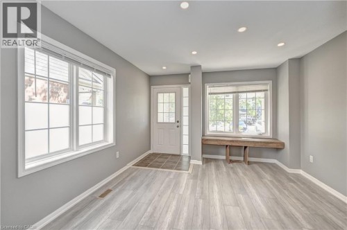 Recessed ceiling lighting, multiple large windows, wood-finish flooring, a glass-paneled entry door, and a built-in window bench - 103 Blackbird Circle, Cambridge, ON 