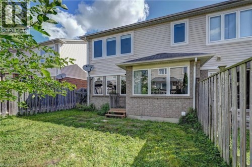 Rear exterior with light-colored siding and a brick-clad lower level - 103 Blackbird Circle, Cambridge, ON 