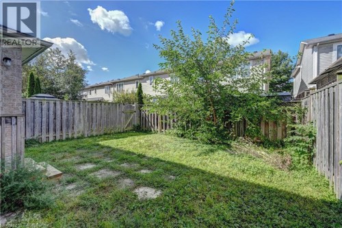 Expansive fenced backyard with a grass lawn, a mature tree, and a wooden gate - 103 Blackbird Circle, Cambridge, ON 