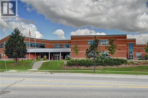 Brick exterior featuring multiple windows, a prominent entrance with steps, and a landscaped front area with mature trees - 103 Blackbird Circle, Cambridge, ON 