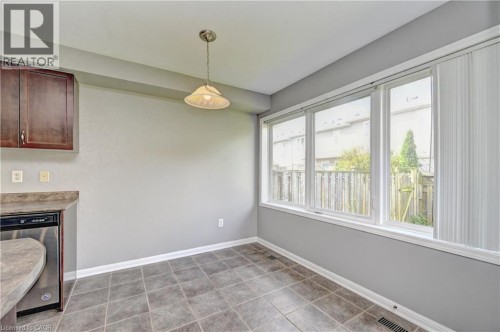 Floor-to-ceiling windows, ceramic tile flooring, built-in dishwasher, dark wood-finish cabinetry, and a curved countertop - 103 Blackbird Circle, Cambridge, ON 